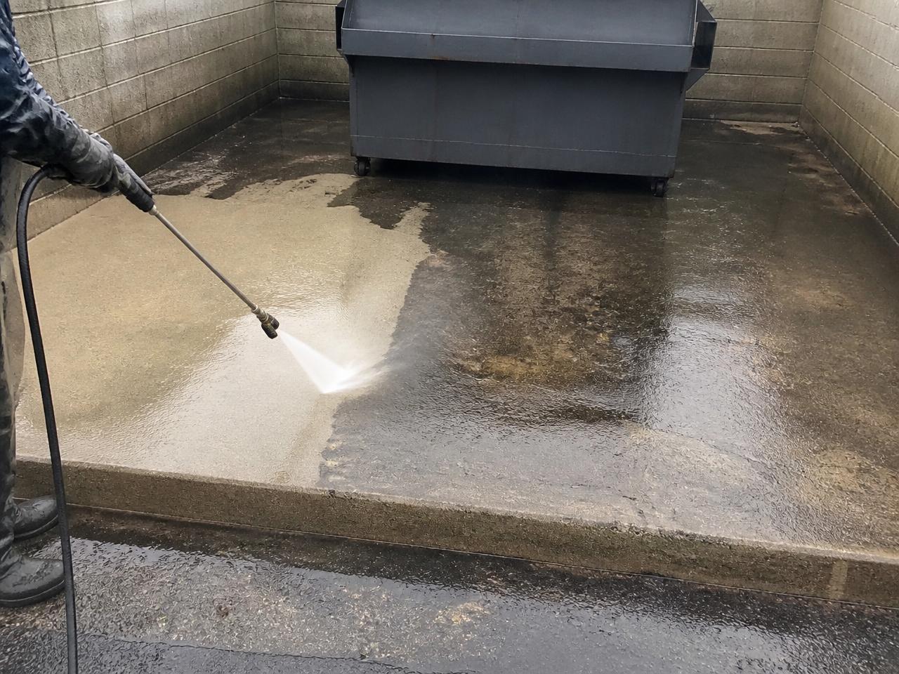 Commercial dumpster pad concrete being pressure washed clean